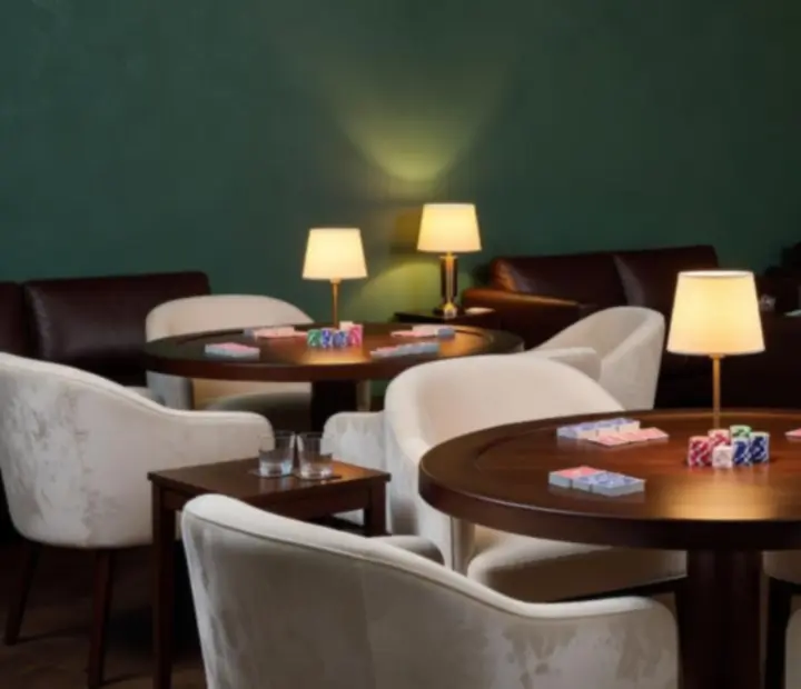 Deep eucalyptus poker lounge interior with timber card tables, warm lamps and lounge seating